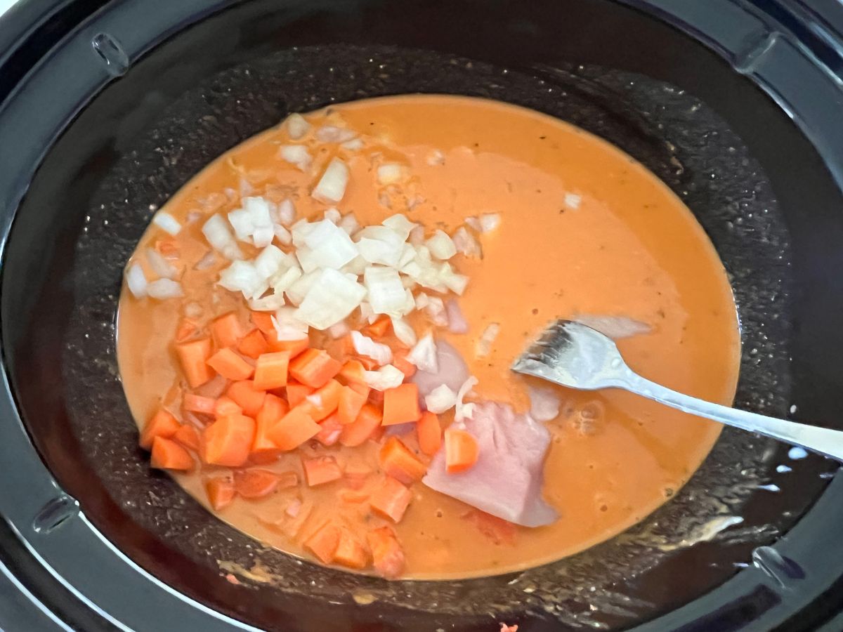 Chicken and chopped veggies added to the peanut sauce mixture in a crockpot.