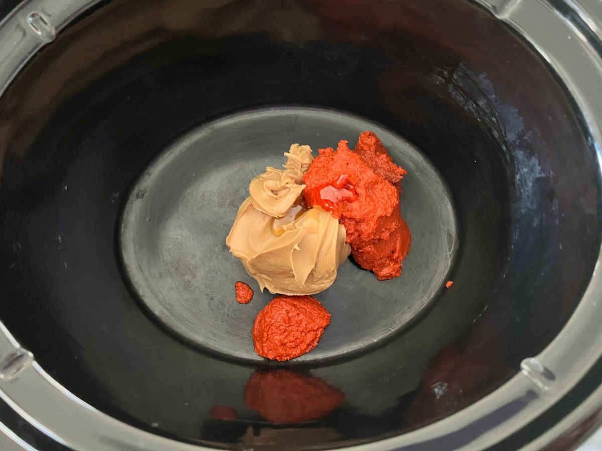 Peanut butter and Thai Red Curry Paste added to the crock pot for Slow Cooker Satay Chicken.