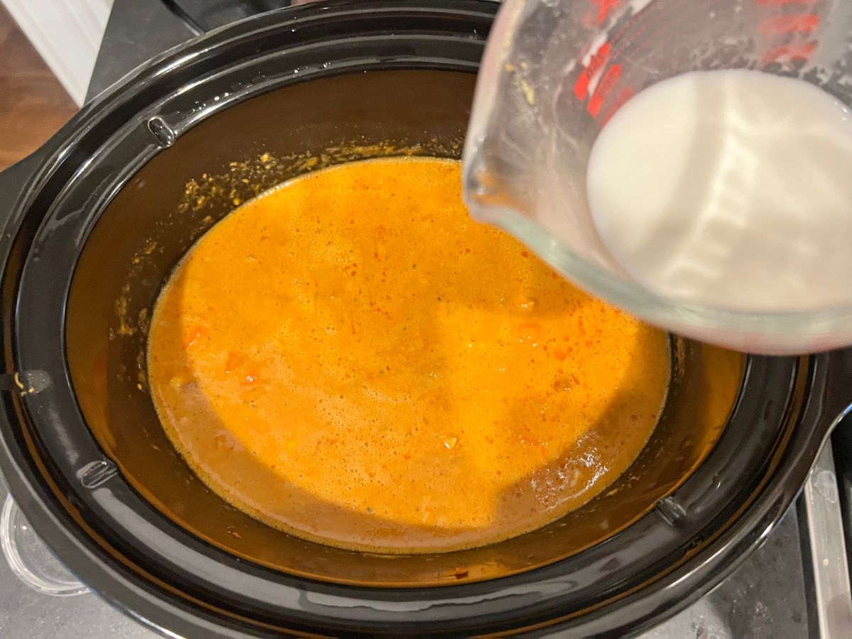 Cornstarch slurry being poured into the peanut butter mixture in a crockpot.