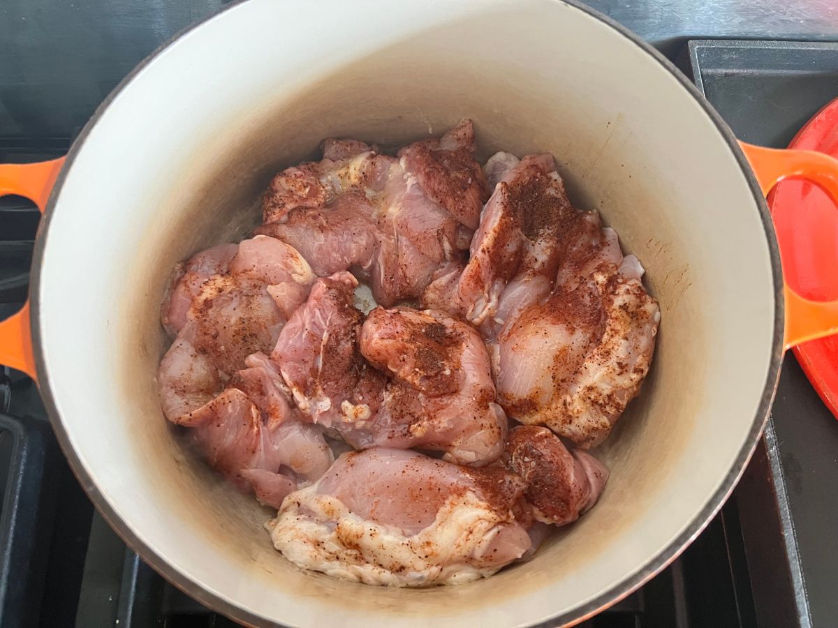 Seasoned chicken thighs searing in a Dutch oven.