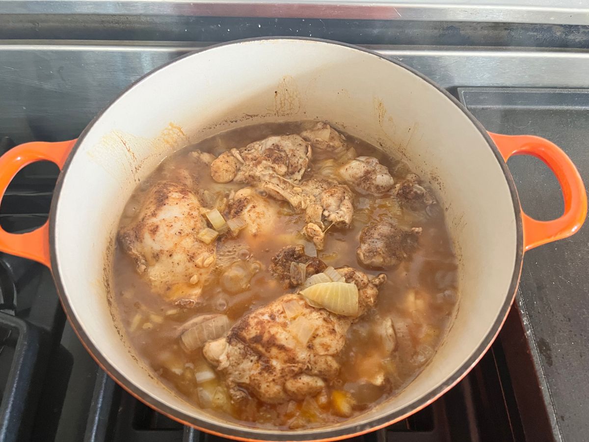 Chicken thighs cooking in the seasoned broth mixture.