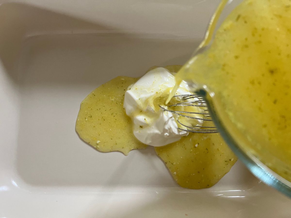 Lemon juice and broth being poured into a baking dish with sour cream.