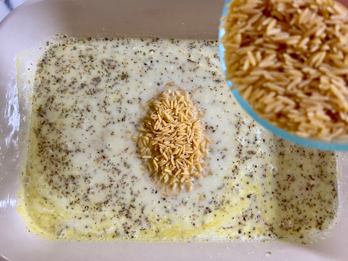 Orzo being poured into the baking dish.