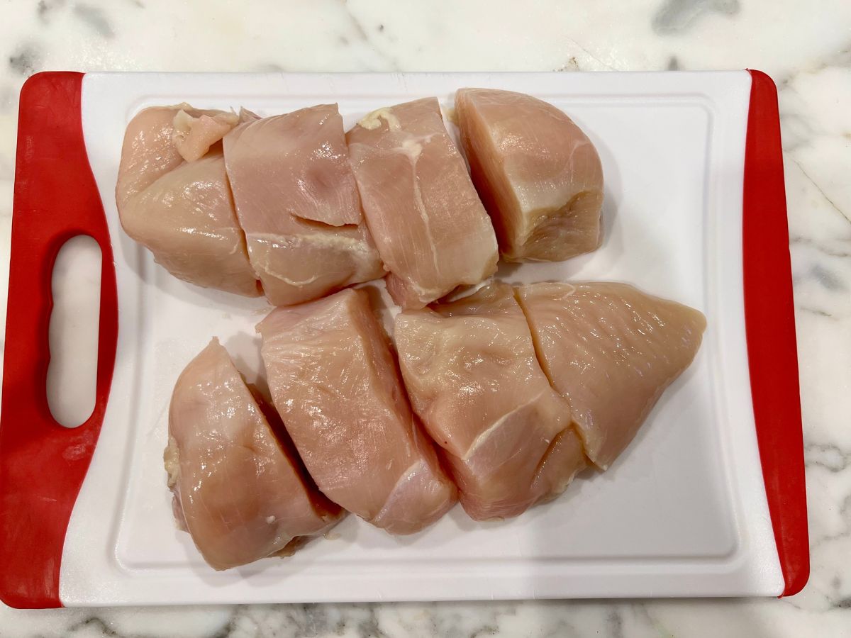 Chicken breasts on a cutting board cut into 4 chunks.