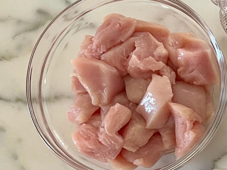 1 inch pieces of chicken breast added a glass mixing bowl for Slow Cooker Satay Chicken.