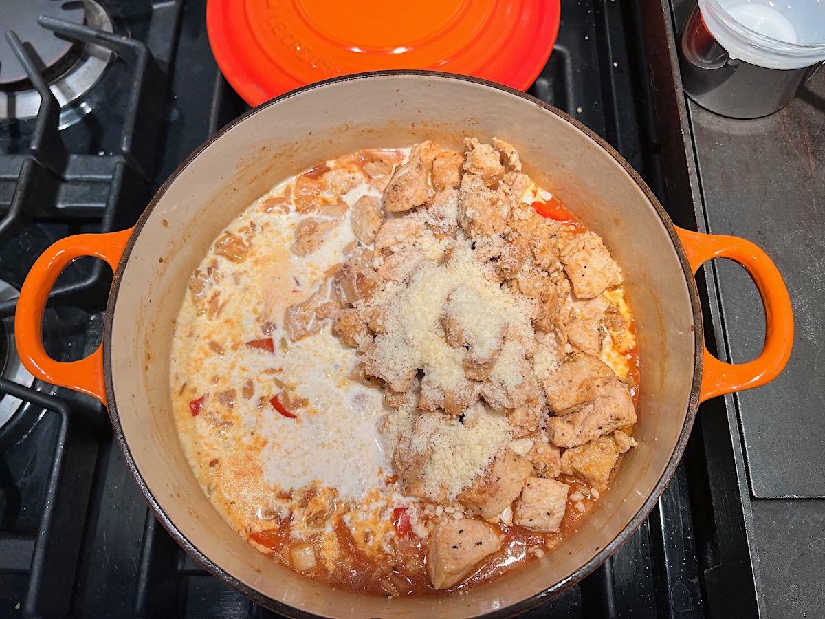 Parmesan and chicken added back to the orzo in a pot on stove for Chicken Chorizo Orzo.