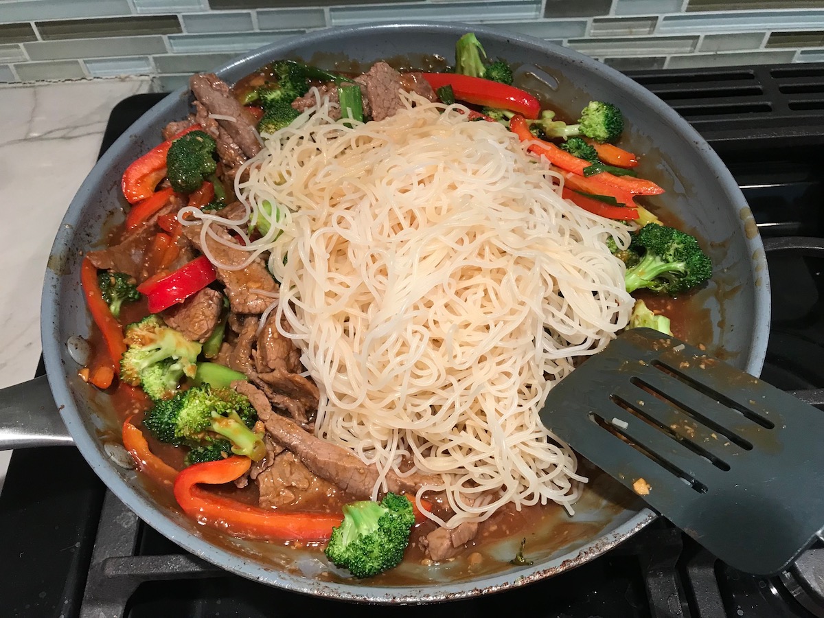 Cooked Rice noodles added to pan with steak and veggies for Beef and Broccoli Noodles recipe.