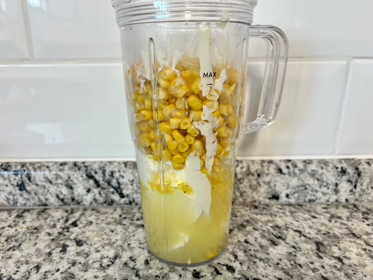 Blender filled with broth, cream cheese, and corn before blending for the Mexican Street Corn Casserole recipe.