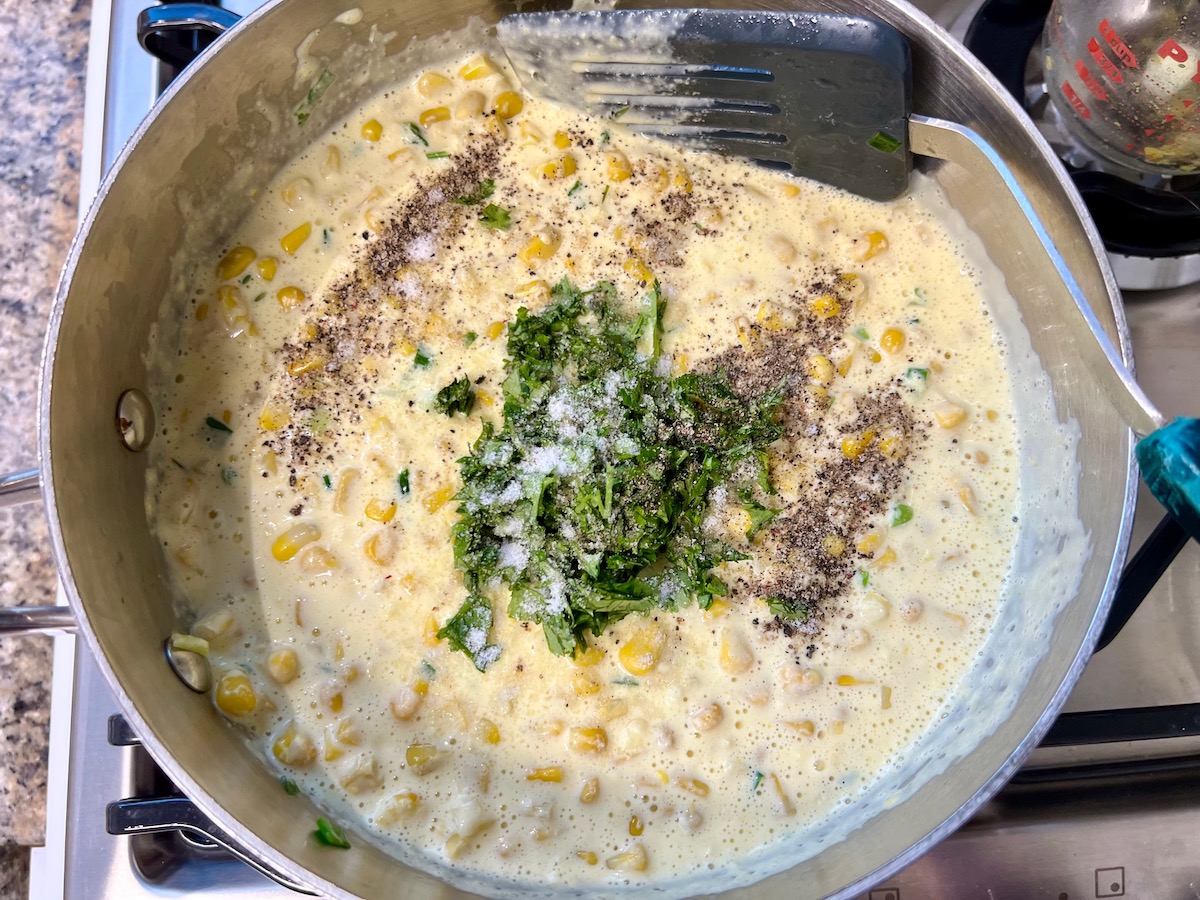 Corn, corn and cream cheese mixture, silantro, salt, and pepper all added to pot with scallions for the Mexican Street Corn Casserole recipe.