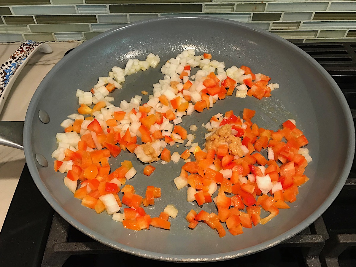 Diced red pepper, onions, and minced garlic in a frying pan cooking for the Vegetarian Sloppy Joes recipe.