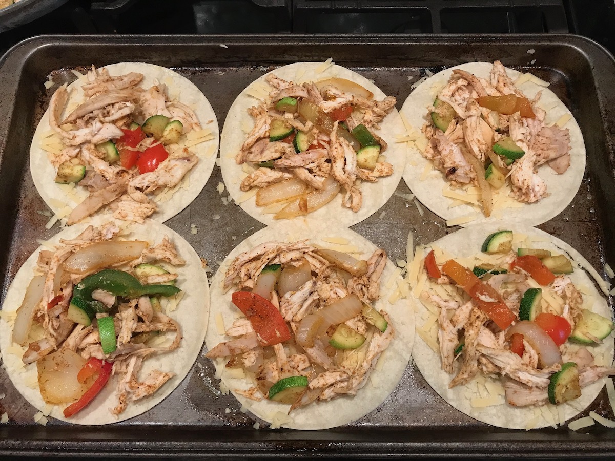 Cooked shredded chicken, onions, red peppers, and zucchini added to 6 flat corn tortillas before cooking Rotisserie Chicken Quesadillas recipe.