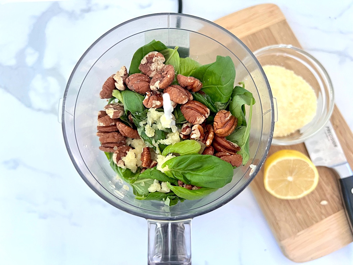Nuts, basil, olive oil, and garlic in food processor before being blended for Pesto Pasta with Tomatoes.