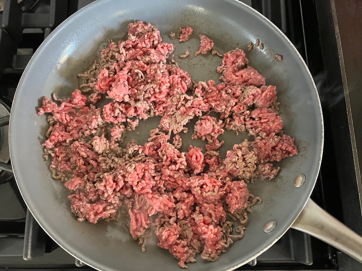 Ground beef cooking in a skillet on the stove for Ground Beef Gnocchi skillet recipe.