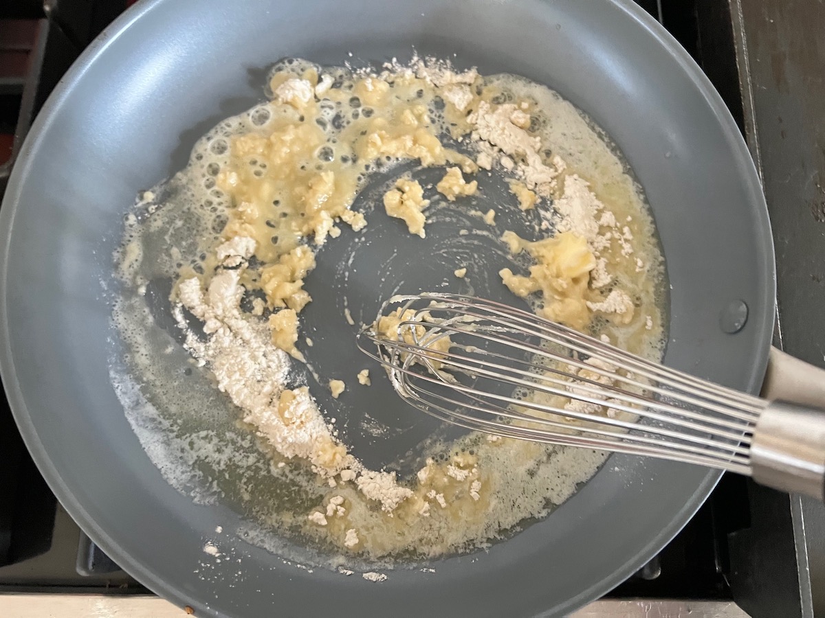 Flour and butter mixed into a roux in a large frying pan on the stove for Mushroom Alfredo Fettuccine pasta.