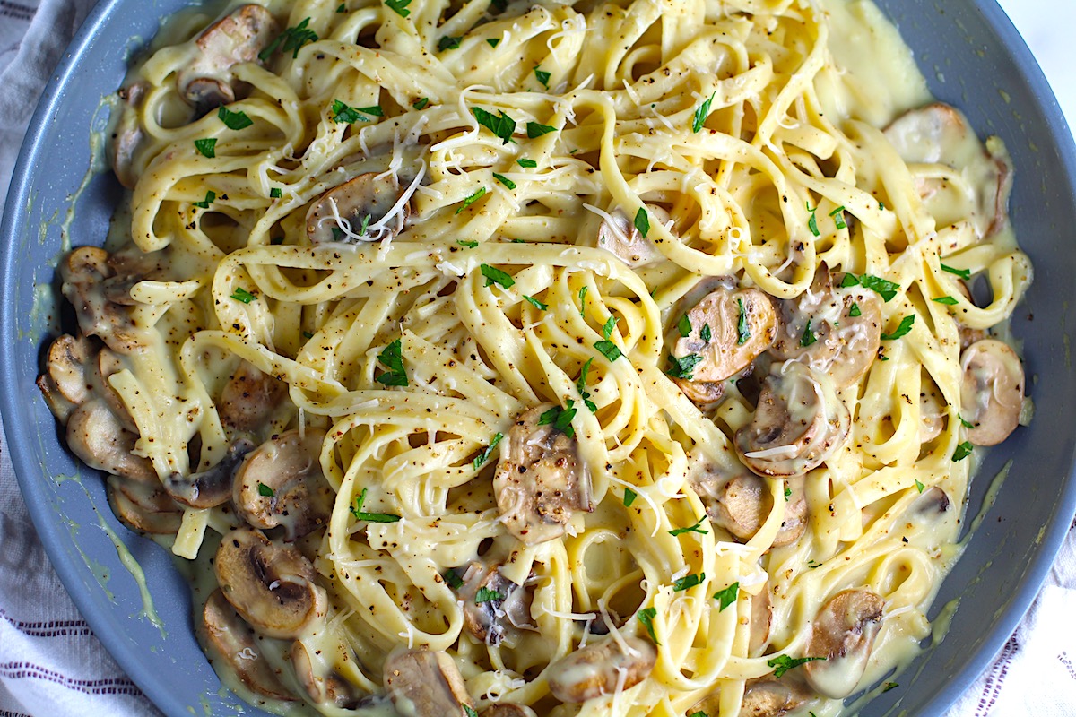 Mushroom Alfredo Fettuccine pasta in a pan with parsley sprinkled on top.