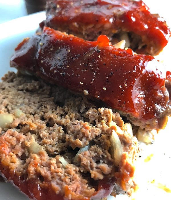 Close up picture of sliced meatloaf with ketchup on top. This 5-Ingredient Easy Meatloaf recipe may be short on ingredients, but it is loaded with flavor. The lack of breadcrumbs means you don't have them soaking up the juices, so the meat stays moist - and it's gluten free too! Parmesan cheese, onion, egg, ketchup, salt, and pepper are all that go into this yummy loaf of goodness!
