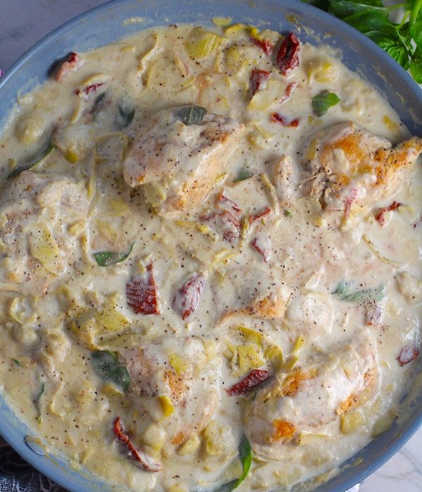 Close up of Skillet Artichoke Chicken with sun dried tomatoes, basil, garlic, in cream sauce. #skilletchicken #skilletdinner #chicken #easydinner #familydinner #italian #tuscanchicken